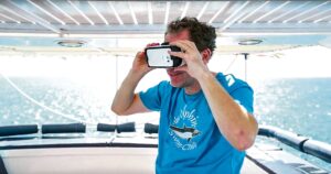 Man staat op de boeg van een schip en kijkt in zijn virtual reality bril