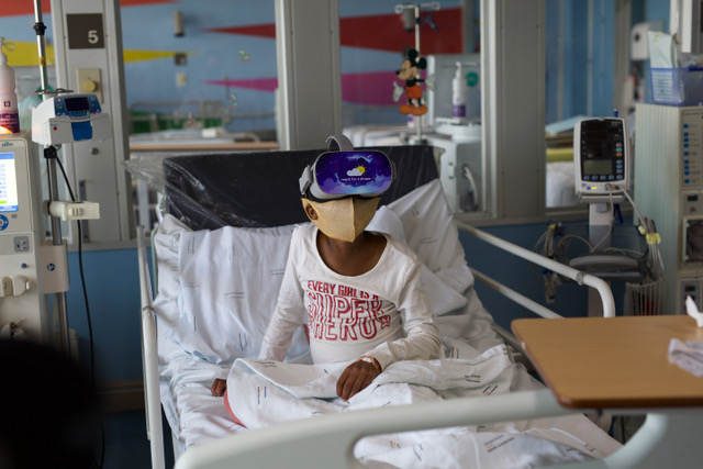 A child in a hospital bed wearing a virtual reality headset